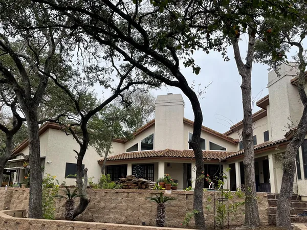 A coursed stone retaining wall holding a planted bank in front of a stucco house