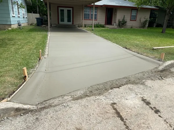 A finished concrete driveway running up to a brick house