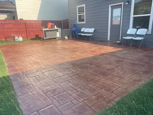 A stamped and stained concrete patio in a fenced back yard