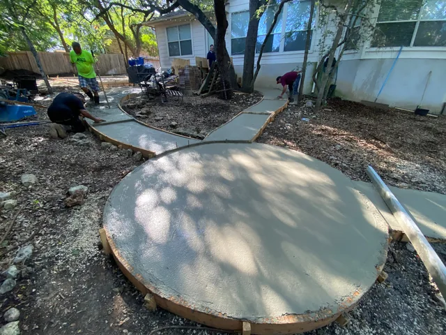 The crew placing a curved concrete pad under live oaks behind a San Antonio house