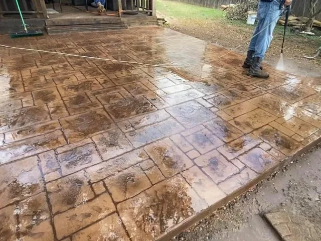 A stamped concrete surface being stained, with the colour still wet